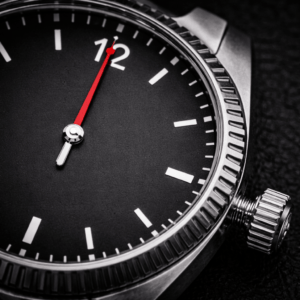 Close-up of a mechanical watch showing hacking seconds with the red second hand stopped at 12 and the crown pulled out