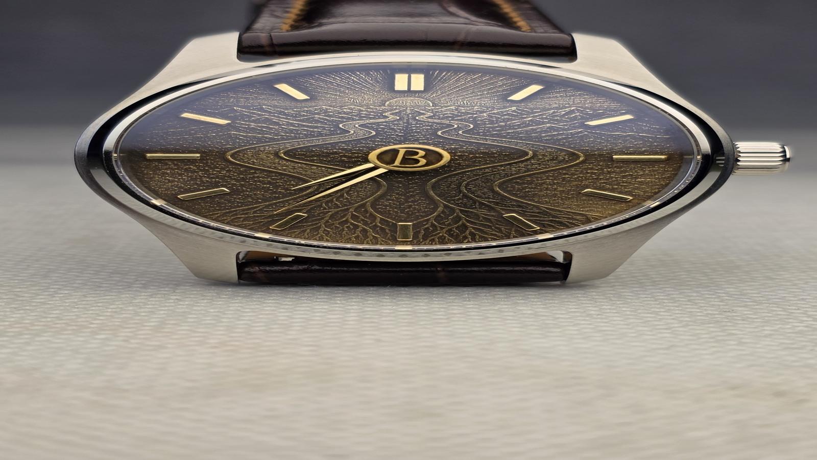 Close view of a custom watch with an engraved dark dial and polished steel case