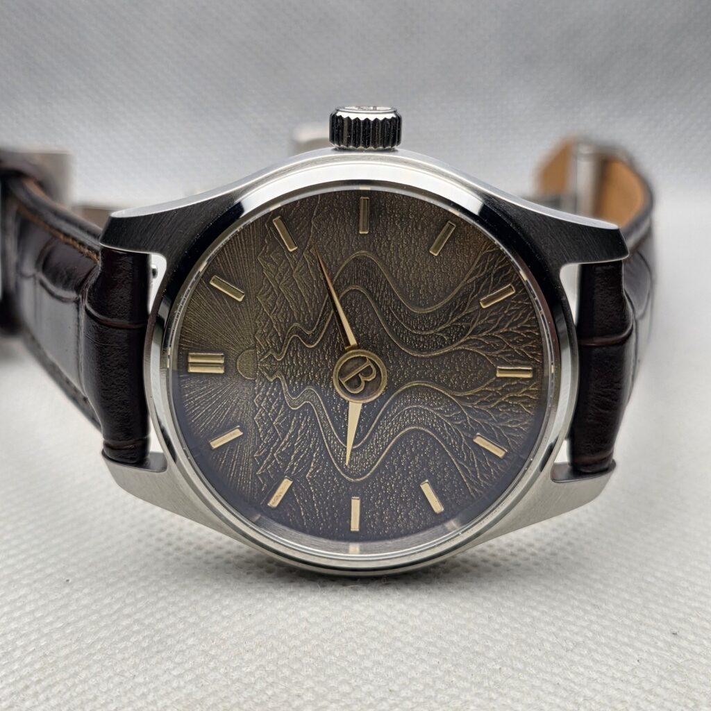 Custom mechanical watch with an engraved dark dial, gold-tone markers, and brown leather strap