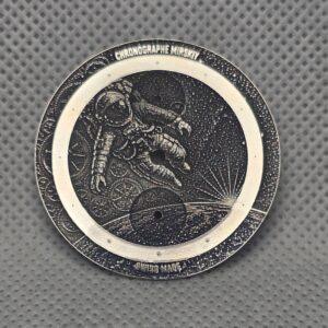 Engraved lettering around an astronaut-themed custom brass watch dial