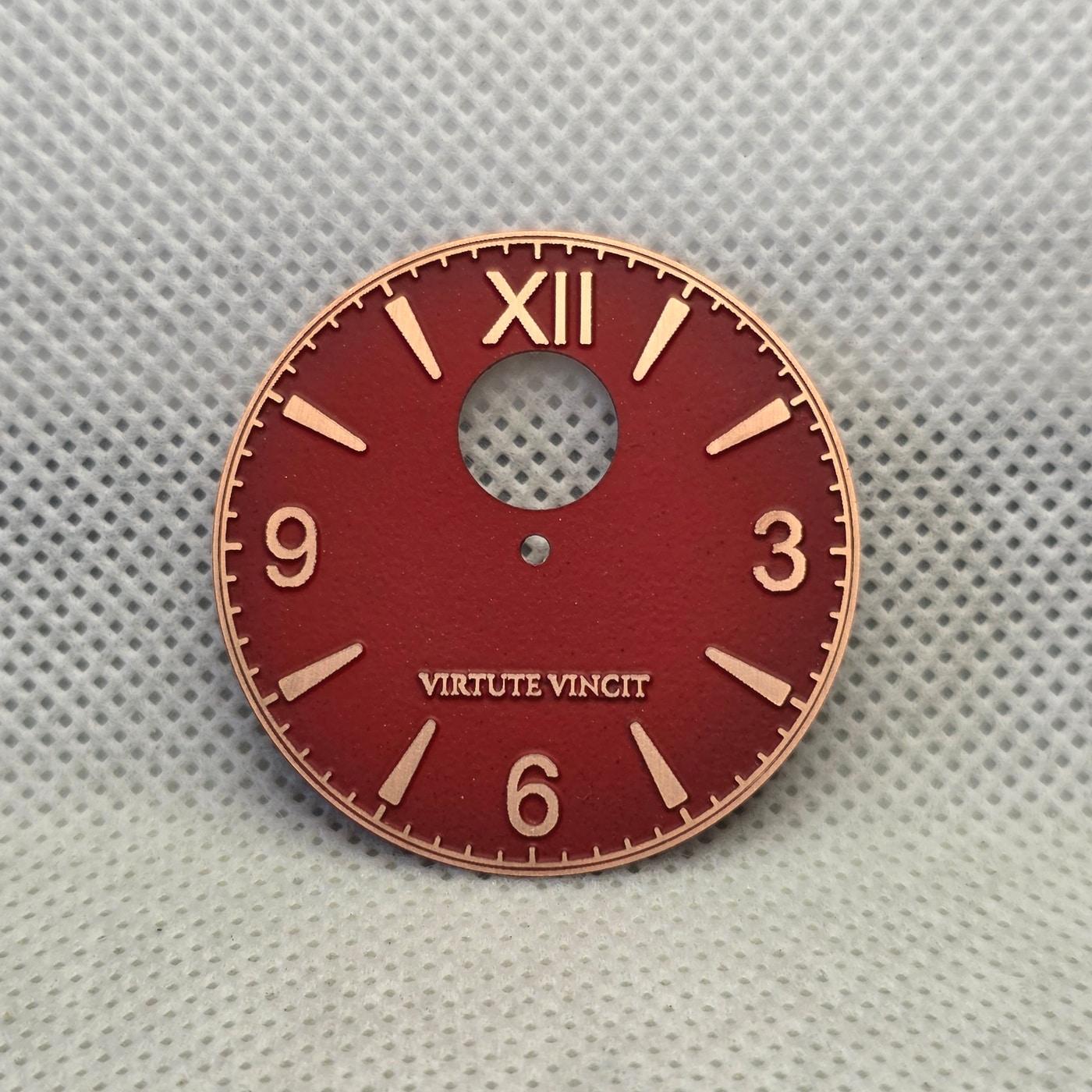 Red enamel watch dial with exposed copper numerals, markers, minute track, and Virtute Vincit text