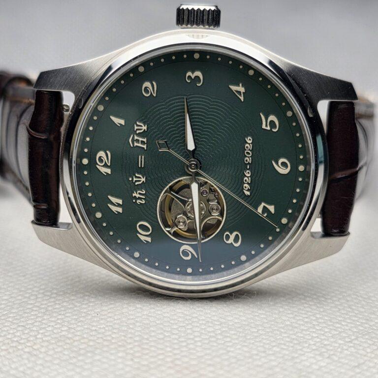 Green mechanical watch dial carrying the Schrodinger equation and an open-heart display