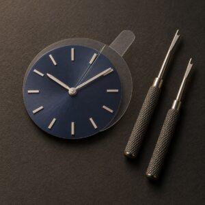 Editorial illustration of a blue watch dial with a clear slotted protector beneath two silver hands, beside two hand-removal tools
