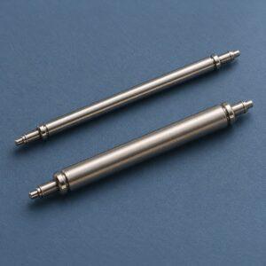 Editorial illustration of two silver-coloured watch spring bars with different tube thicknesses on a blue surface