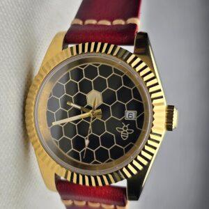Finished Honeycomb watch with a gold-tone case, dark honeycomb dial and burgundy leather strap